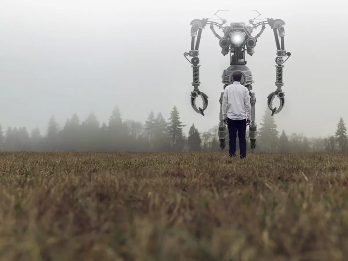 A large robot stands in a field, facing a man.