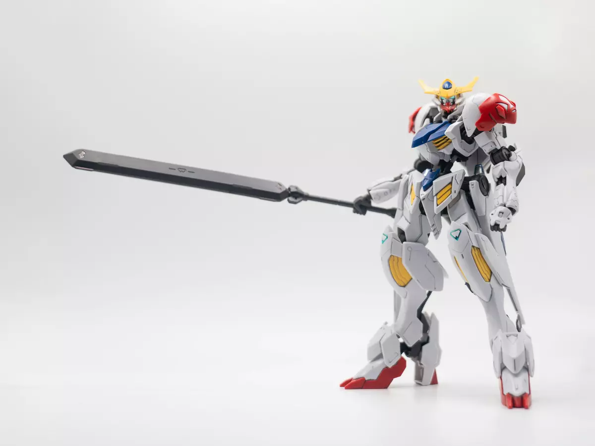 A white and red humanoid robot with a sword stands on a white background.