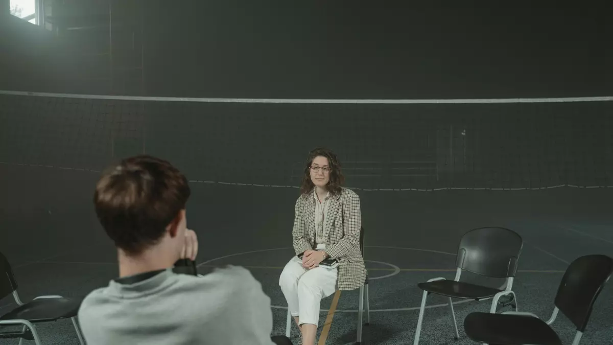 A person sitting in a chair looking at another person in a chair in front of them.