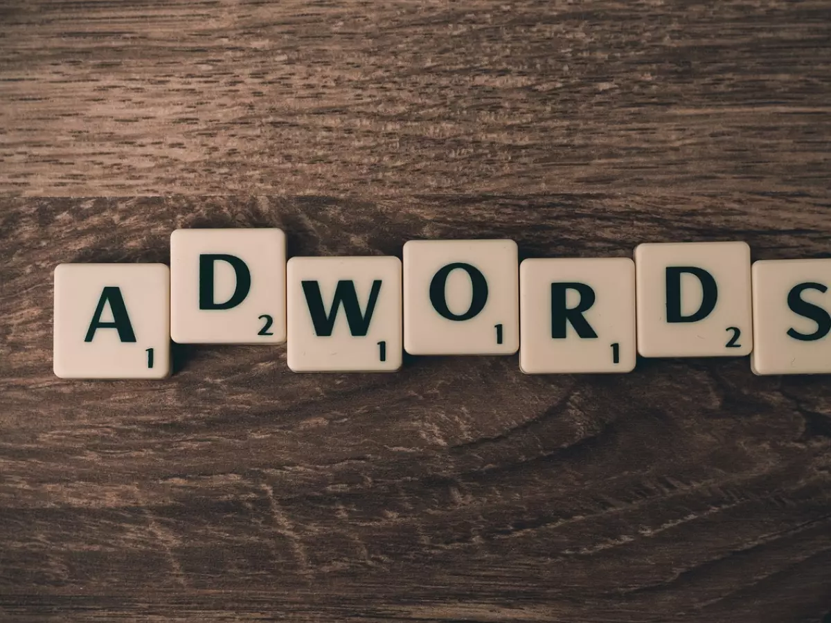 The word "ADWORDS" spelled out using letter tiles on a wooden surface.