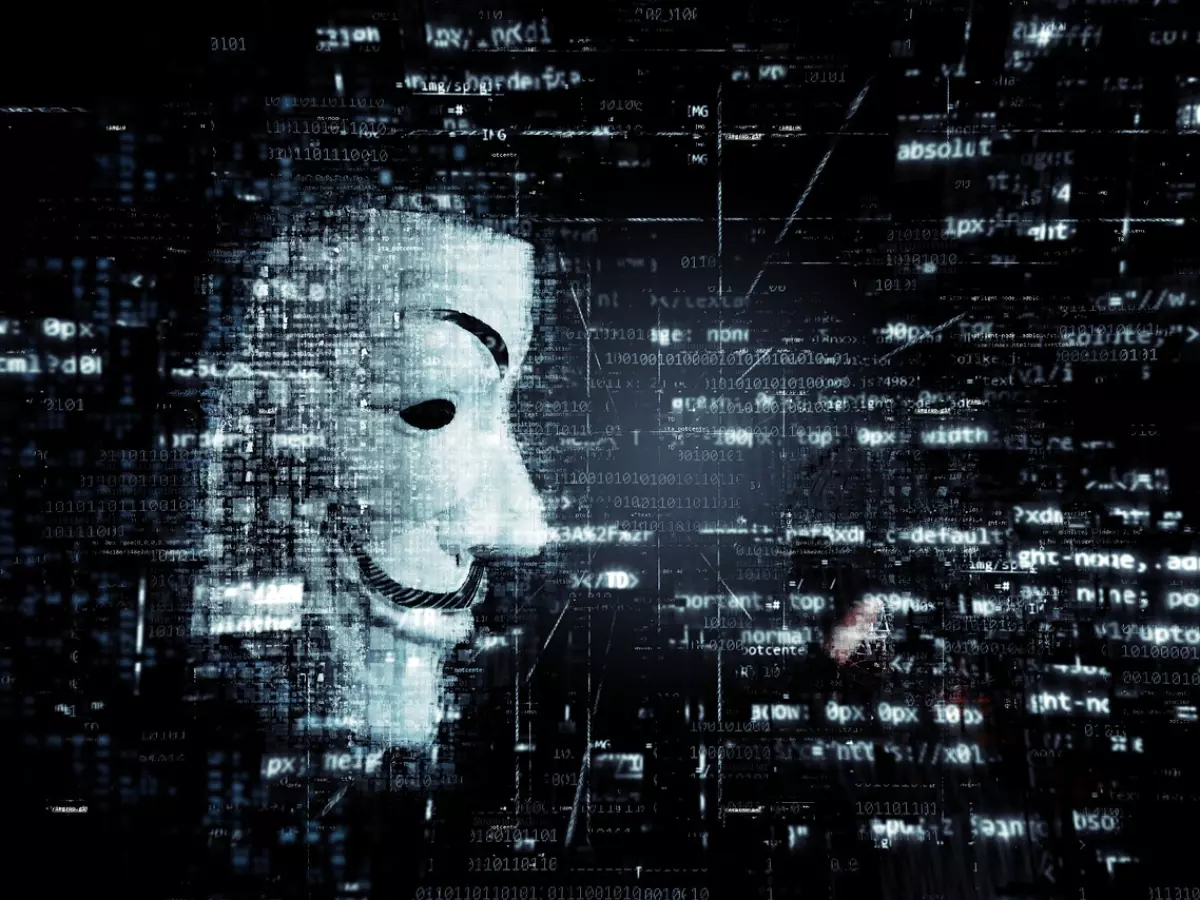 A dark background with white digital code in the form of a blurry digital grid, with a mask of the Anonymous hacker in the center, in grayscale, with the shape of the mask clearly visible.