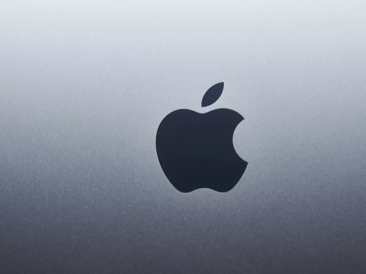 A close-up of the Apple logo, appearing dark against a light background.