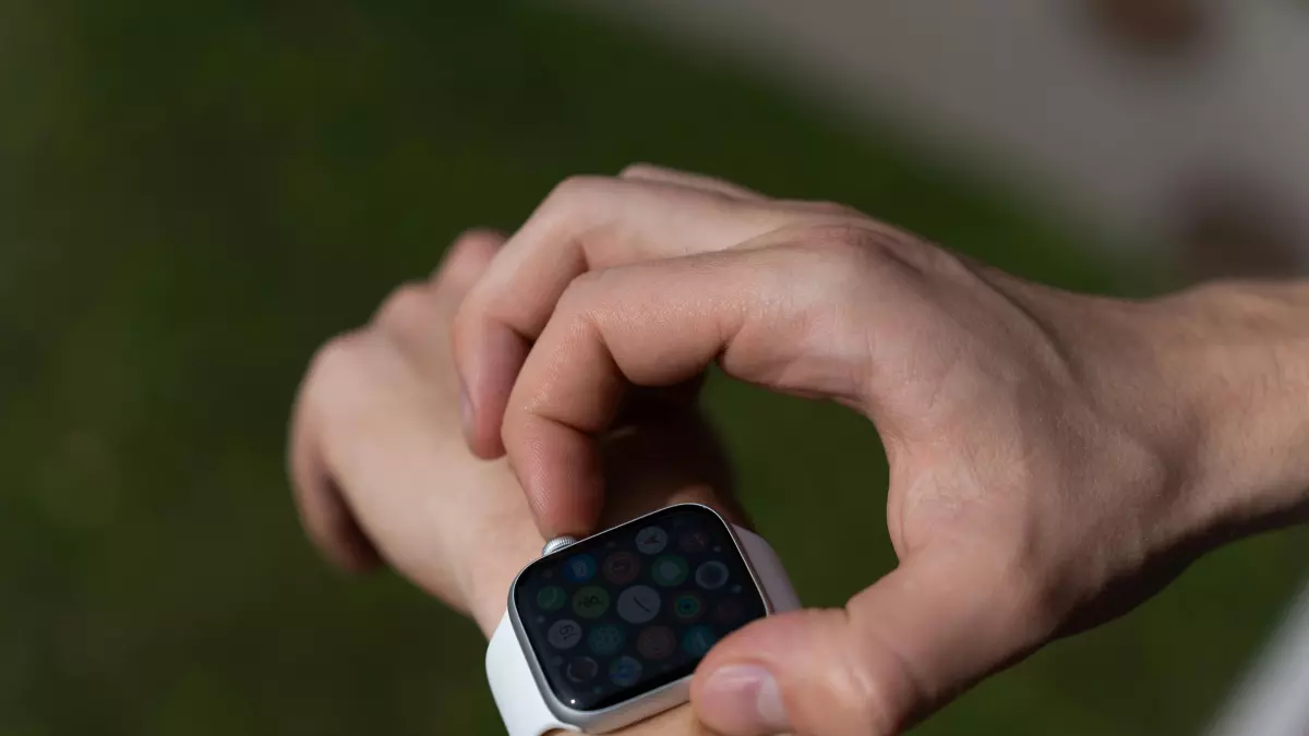 A person is using a smartwatch on their wrist in an outdoor setting.