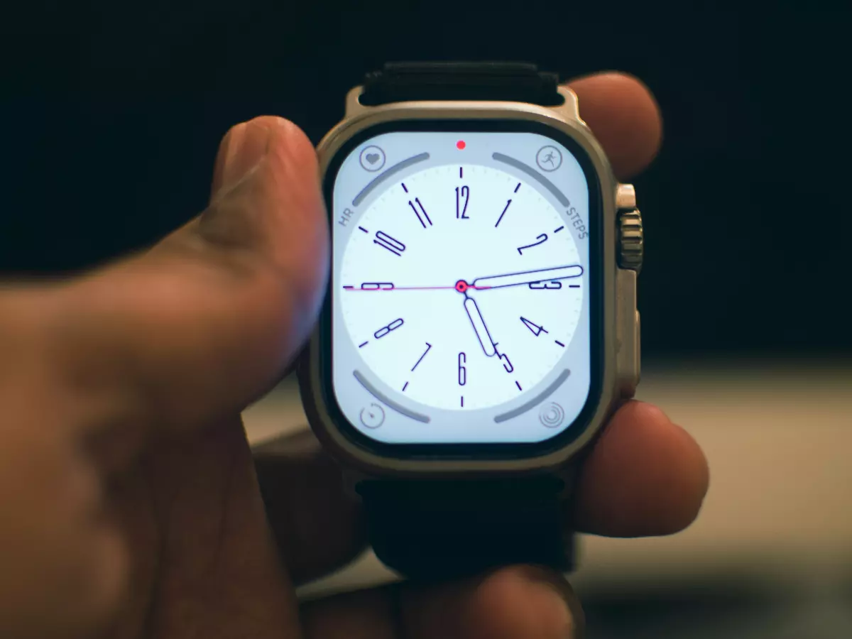 A close-up shot of the Apple Watch Series 10 on a person's wrist. The watch face is showing the time and is in a white background, with classic hands.