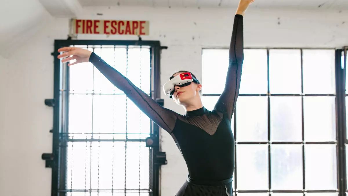 A woman wearing a VR headset is standing in a white room with windows, she has her arms raised. 