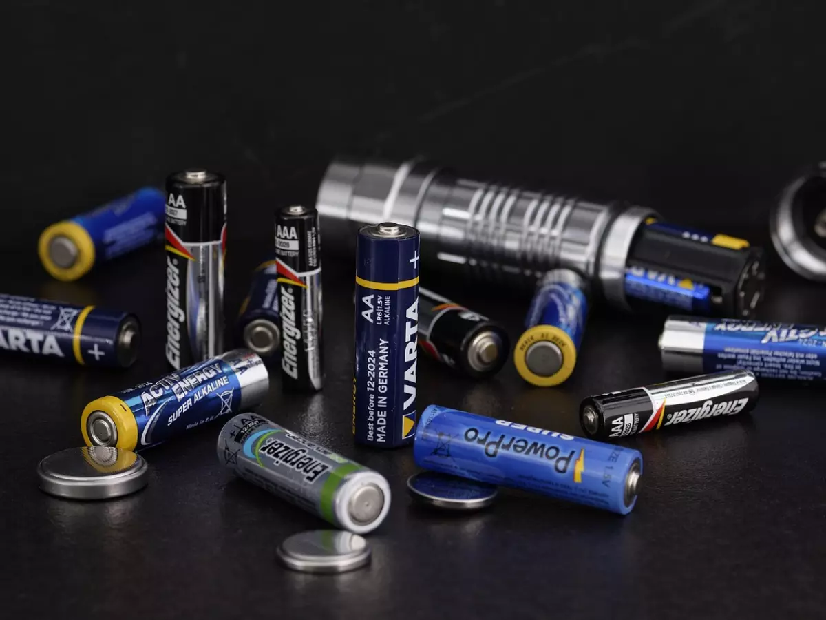 A collection of various sized batteries scattered on a dark surface. 