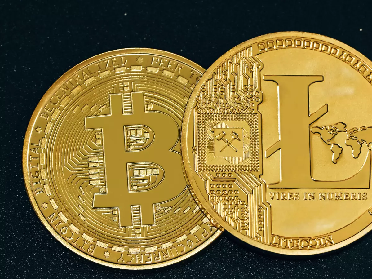 Two gold coins with different symbols, one with a Bitcoin symbol and the other with a Litecoin symbol, against a black background.