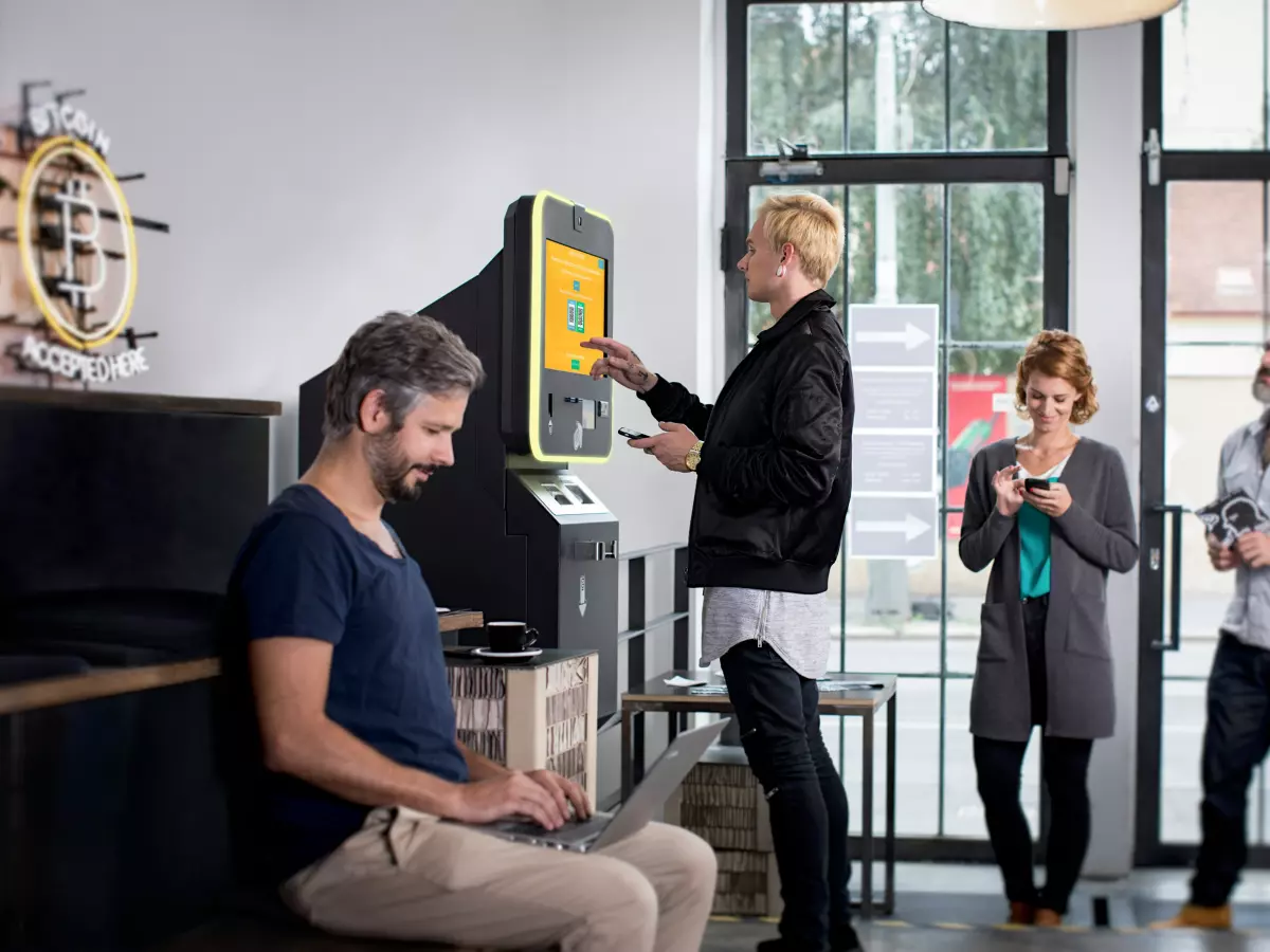 A group of people in a modern setting, using a bitcoin ATM.