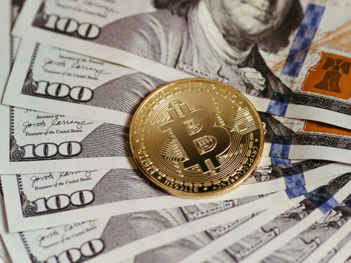 A single Bitcoin coin placed on top of a fan of US dollar bills,  highlighting the value of Bitcoin and its place in the financial world.