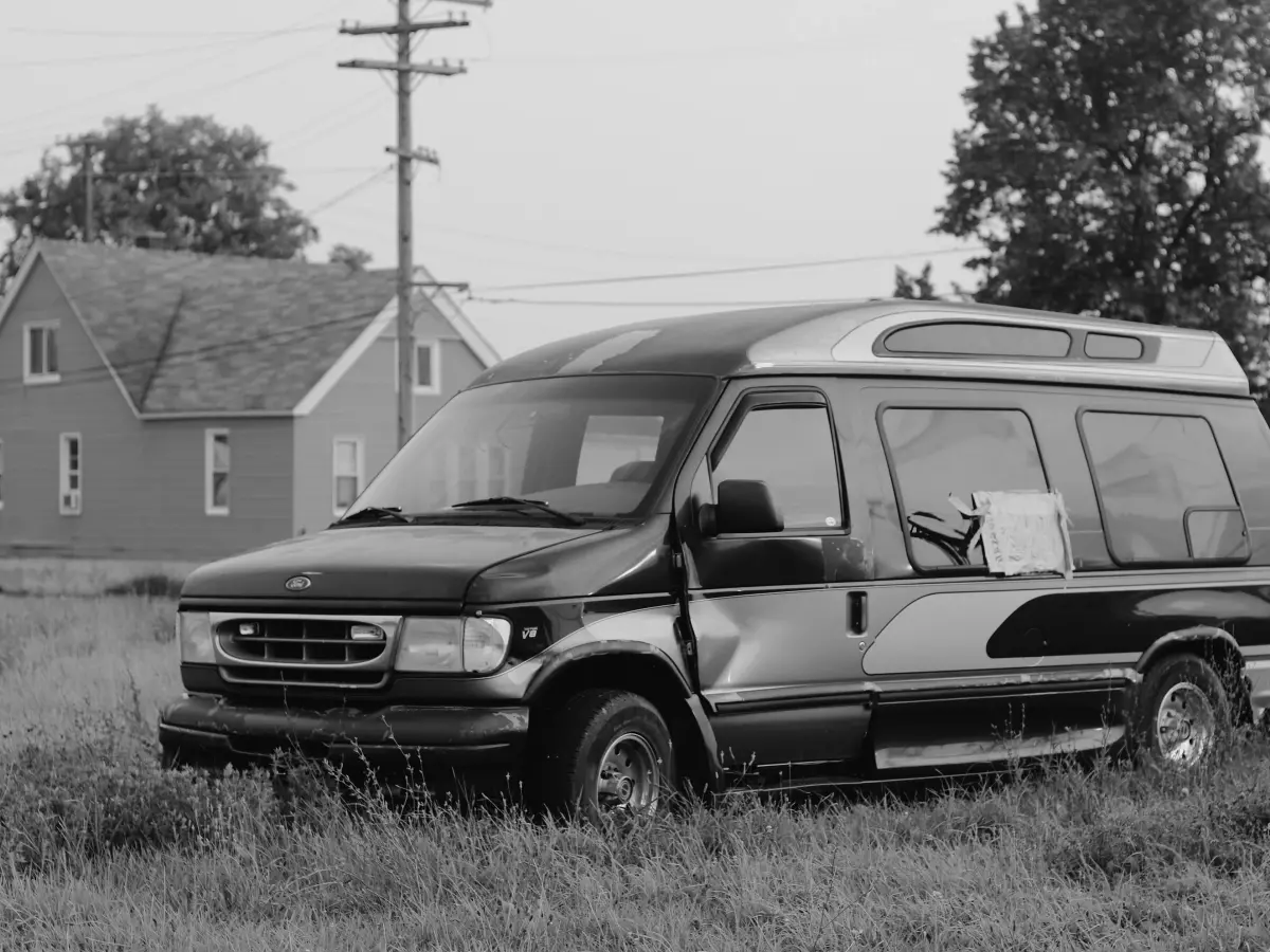 An orange Ford Transit van parked on a street in a city.