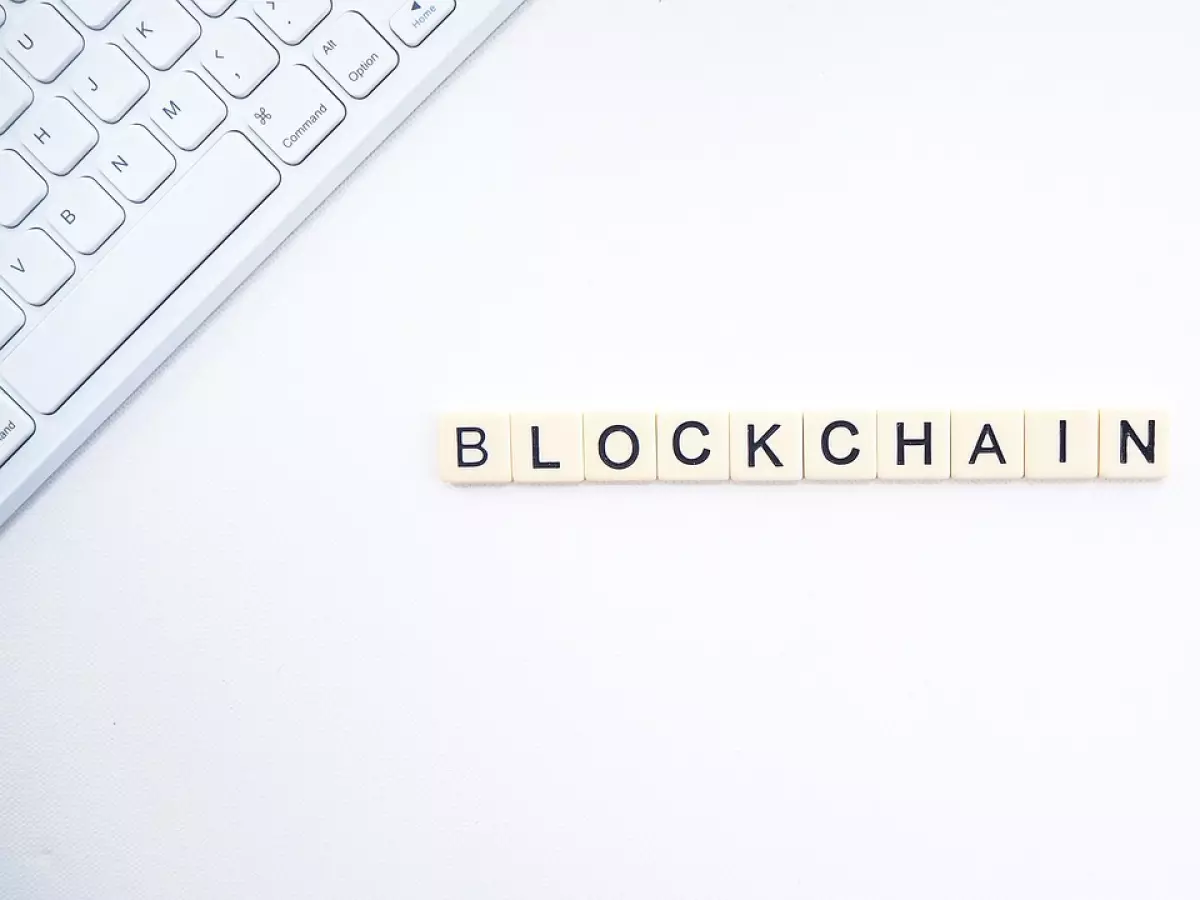 The word 'Blockchain' spelled out with letter tiles on a white surface with a keyboard and a phone in the background.