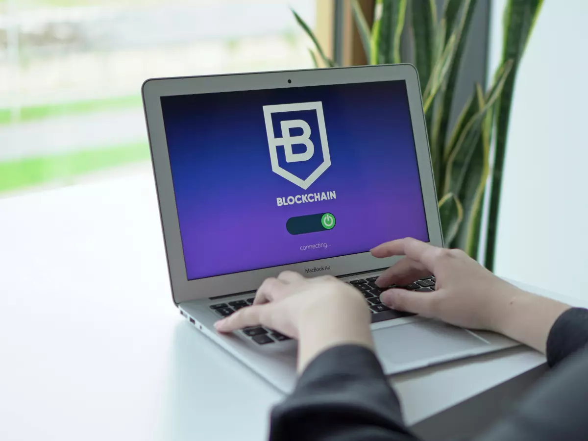 A person is sitting at a desk using a laptop. The screen is displaying a shield with the text "Backup & Security" and a slider showing the security level.