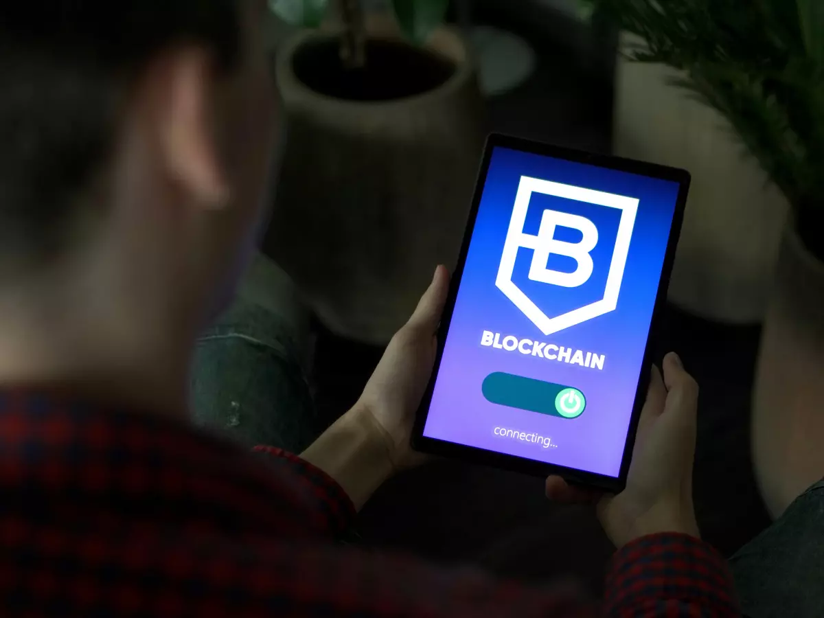 A person's hand holding a smartphone with the blockchain app open. The app is showing the blockchain is connected.