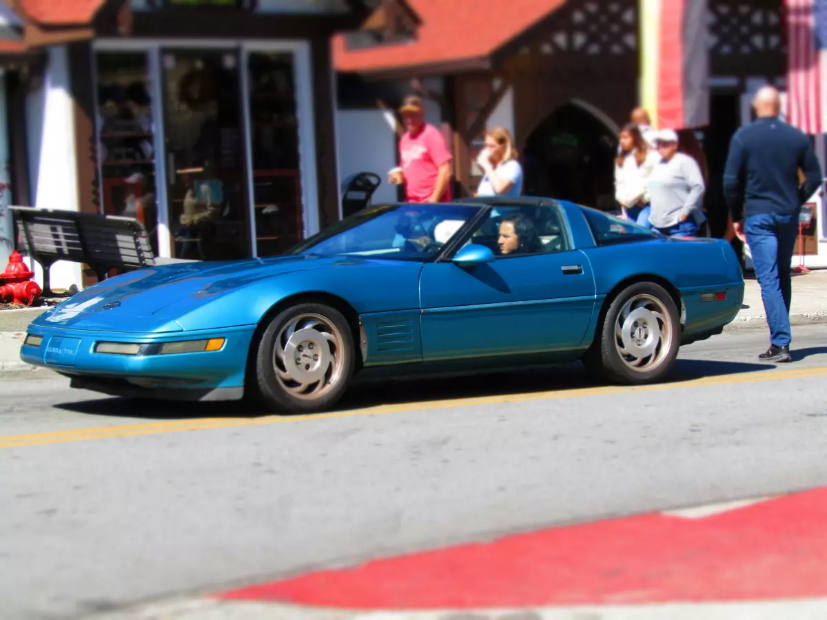 A blue sports car driving on a street.