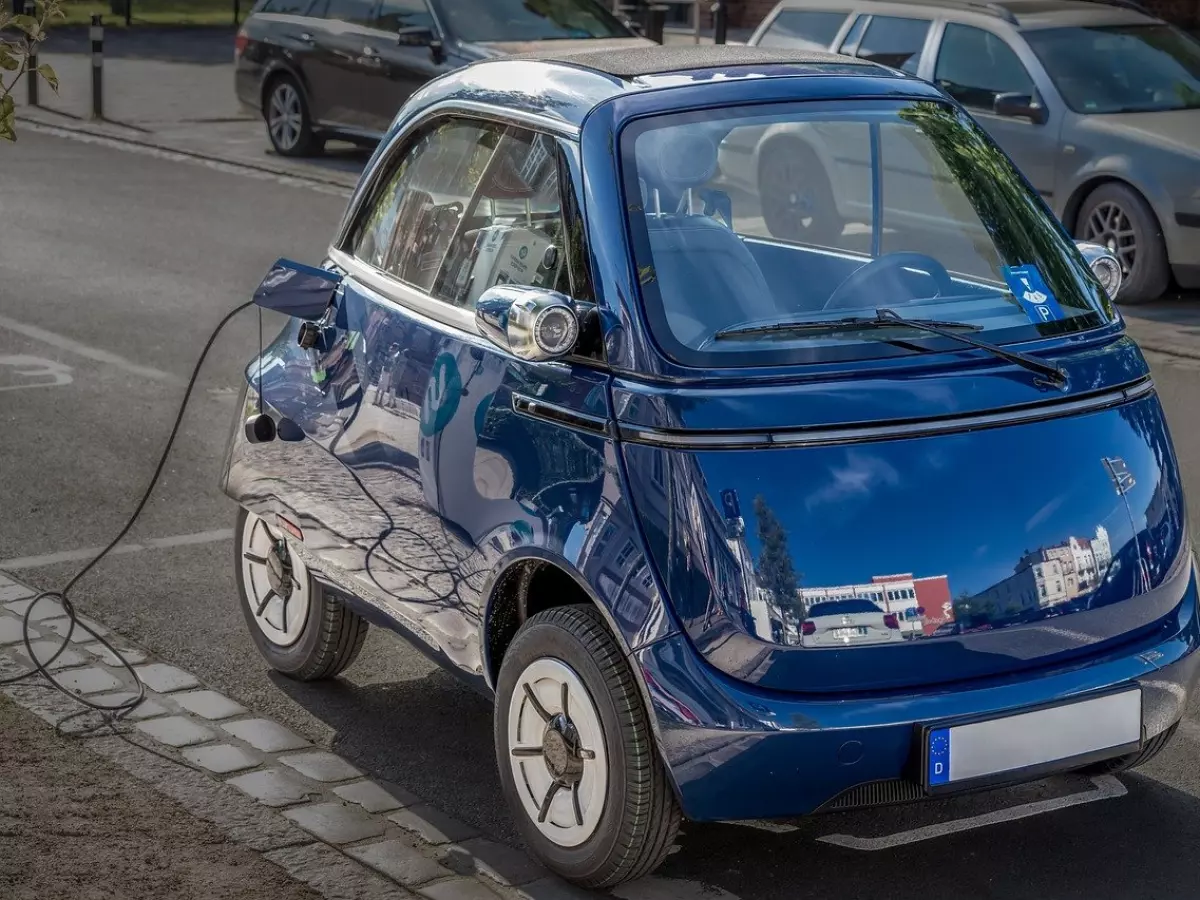 A blue electric car is plugged in.