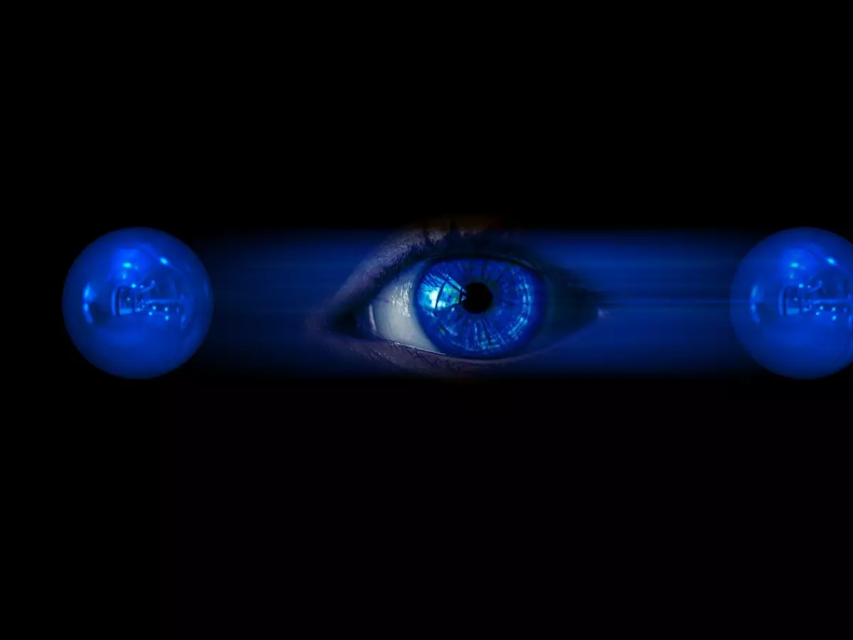 A stylized image of a blue eye surrounded by two blue spheres on a black background.