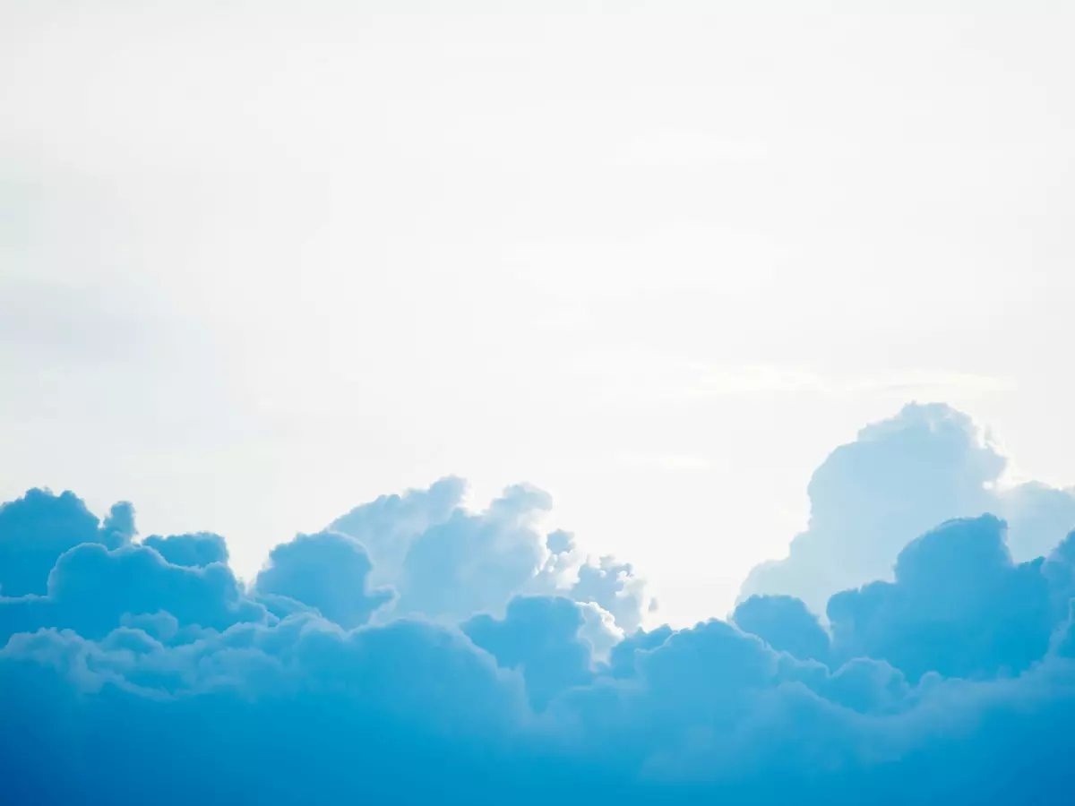 White fluffy clouds against a blue sky with the sun shining through