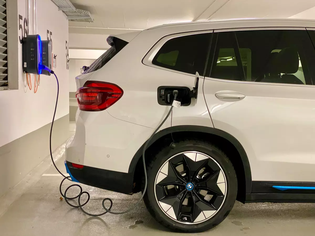 A white SUV plugged into a charging station in a garage.