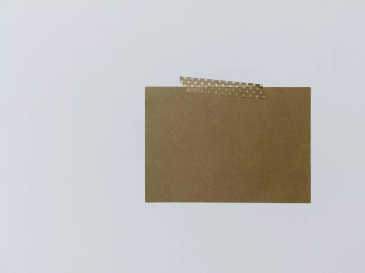 A brown paper card with two strips of patterned tape adhered to it, against a plain white background.