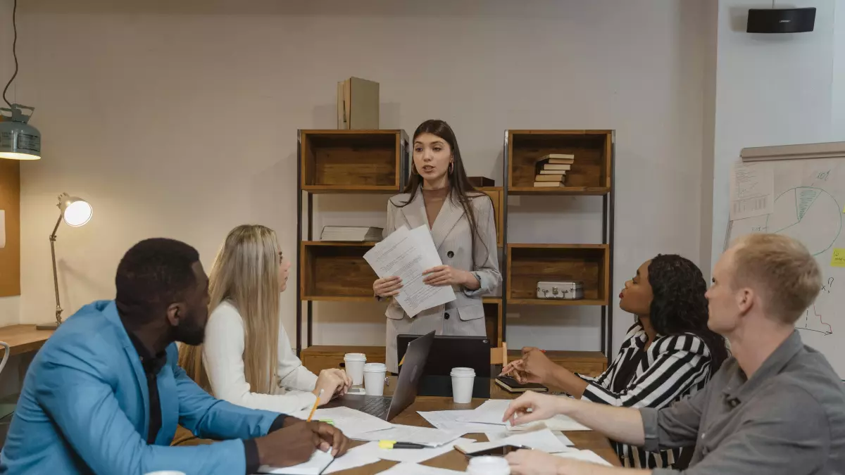 A woman in a meeting room speaking in front of a group of people.