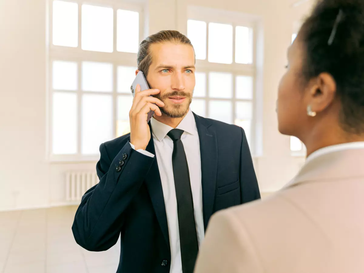 A man in a suit talking on the phone in an office setting.