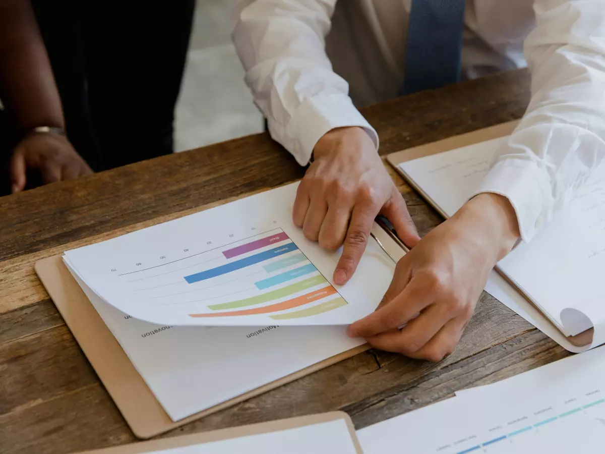 A person is working with a clipboard, analyzing data charts.