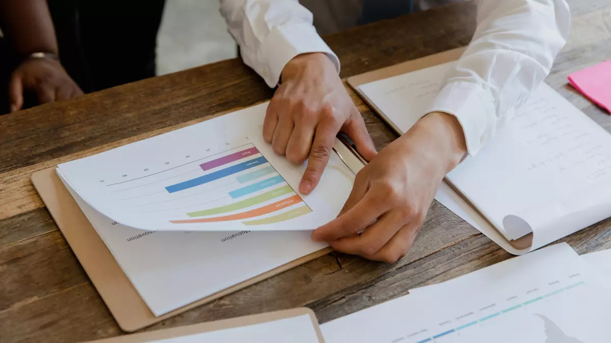 A person is working with a clipboard, analyzing data charts.