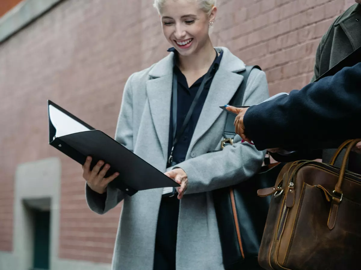 A group of people in business attire walk and talk outside a corporate building