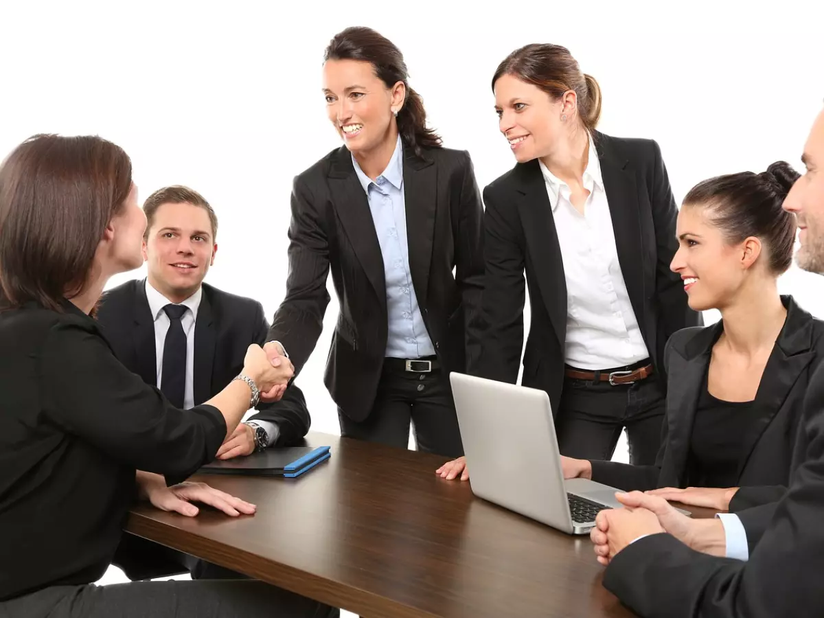 A group of people shaking hands and smiling at each other.