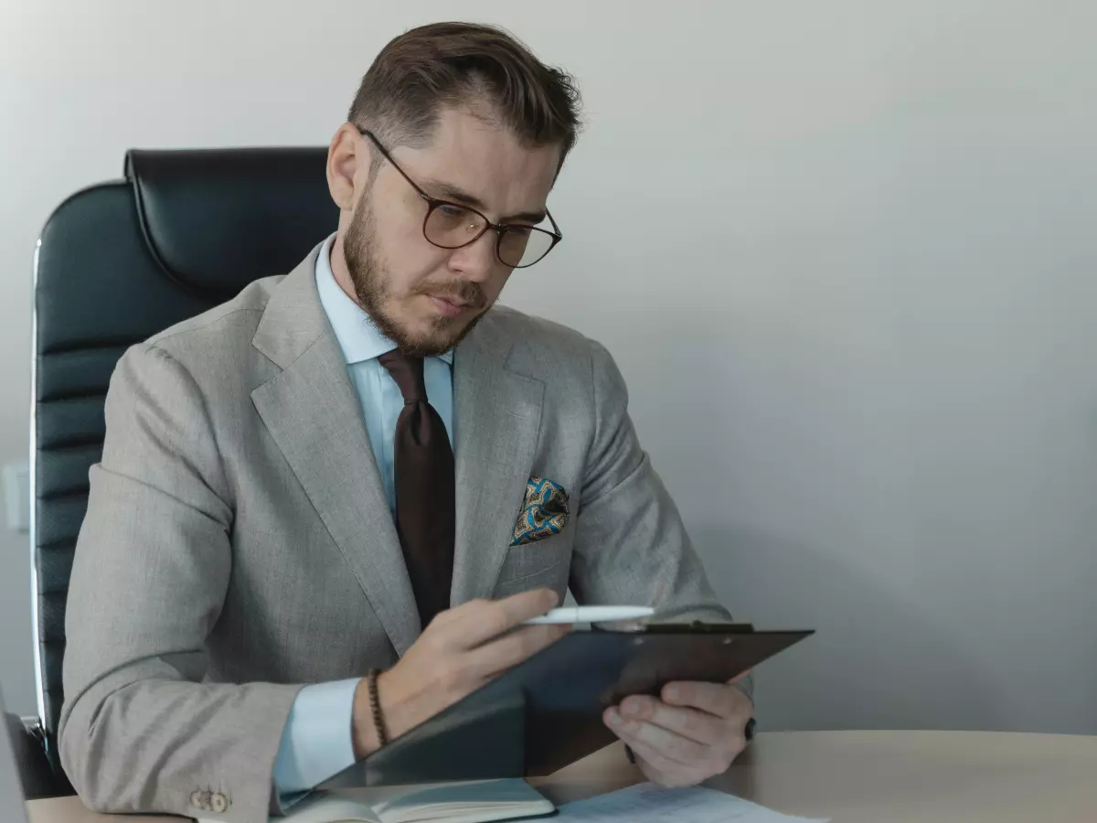 A man in a suit looking at papers in a business setting.