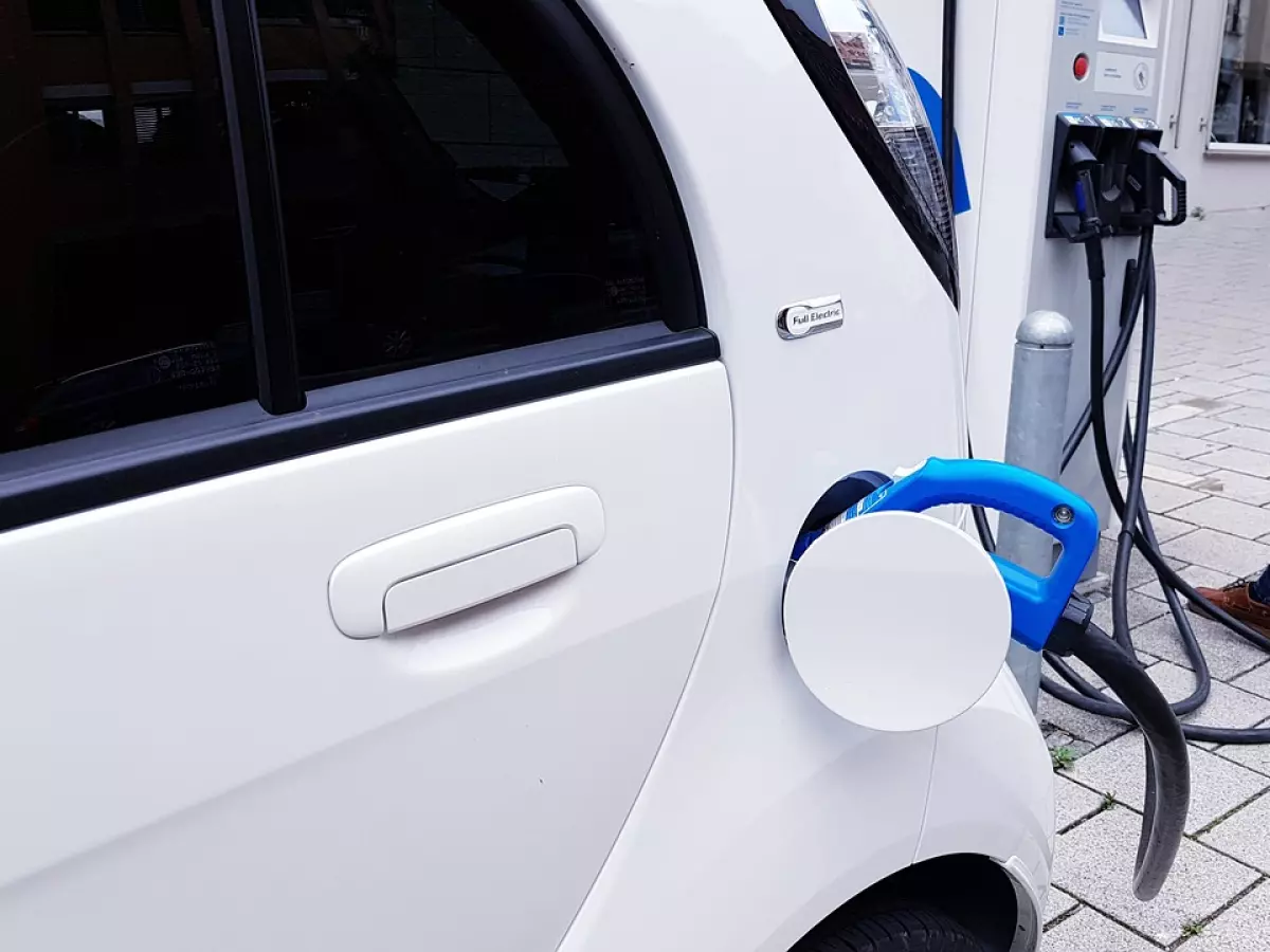 A white electric car is being charged at a public charging station.