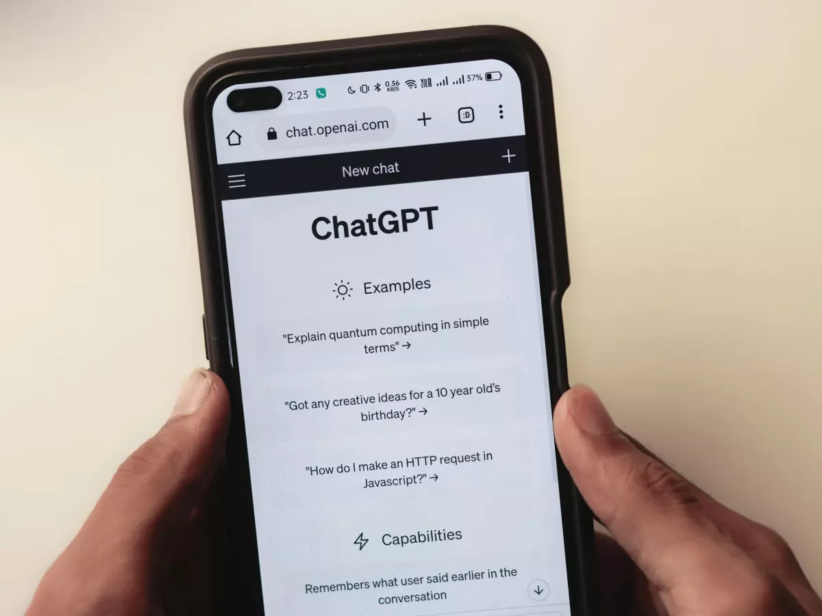 A person's hands holding a smartphone displaying the ChatGPT website.