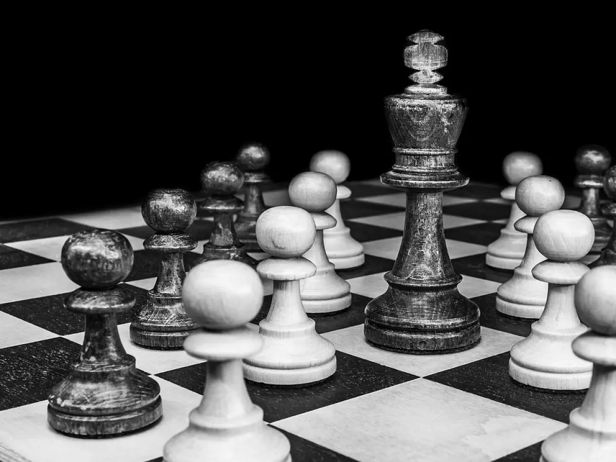 A black and white chessboard with the black king surrounded by white pawns.