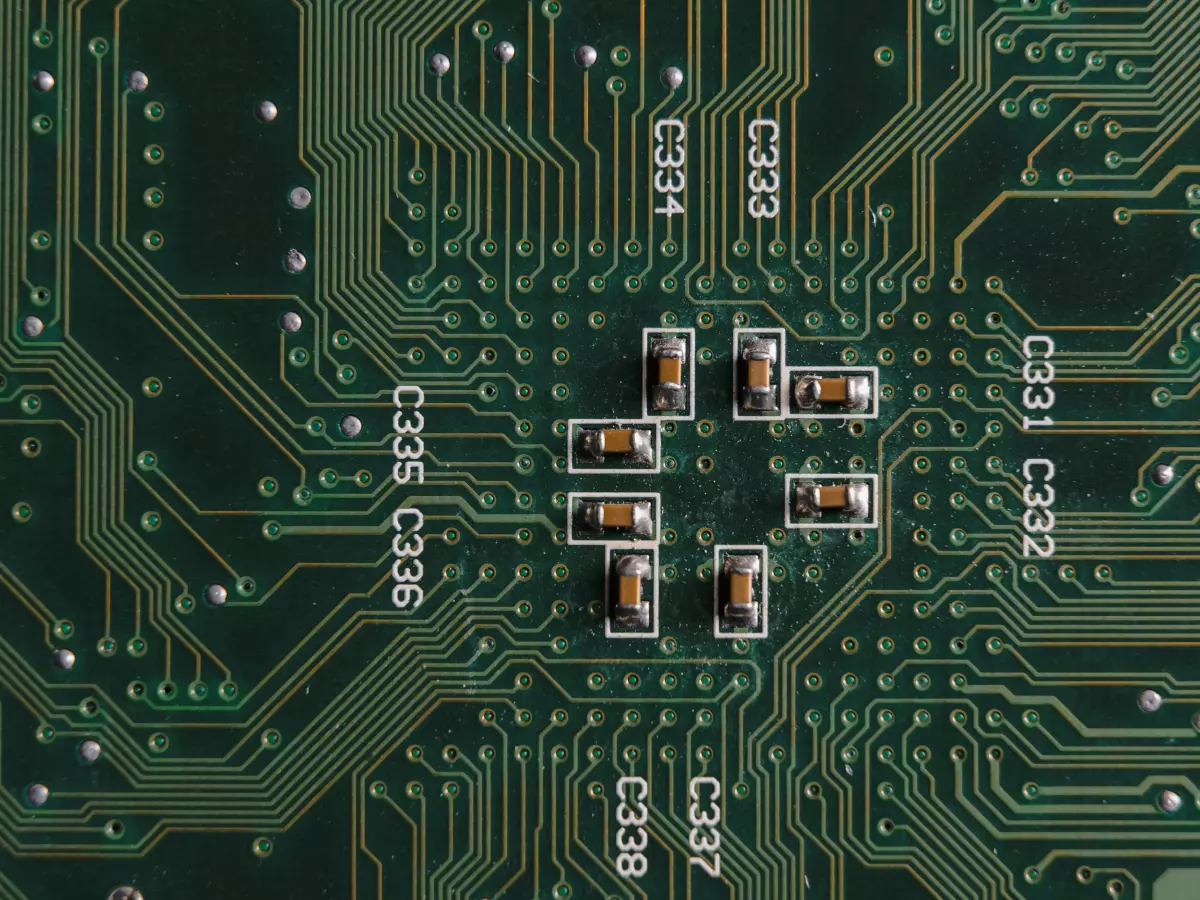 A close-up of a circuit board with a focus on several small components. The background is a green and black patterned circuit board.