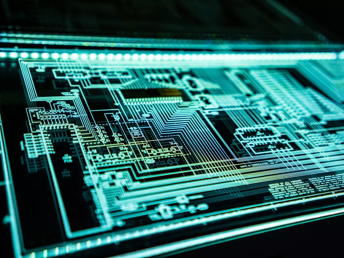 Close up shot of a circuit board, with green lines on a black background, a glass panel is over the circuit board, with lights along the edges.