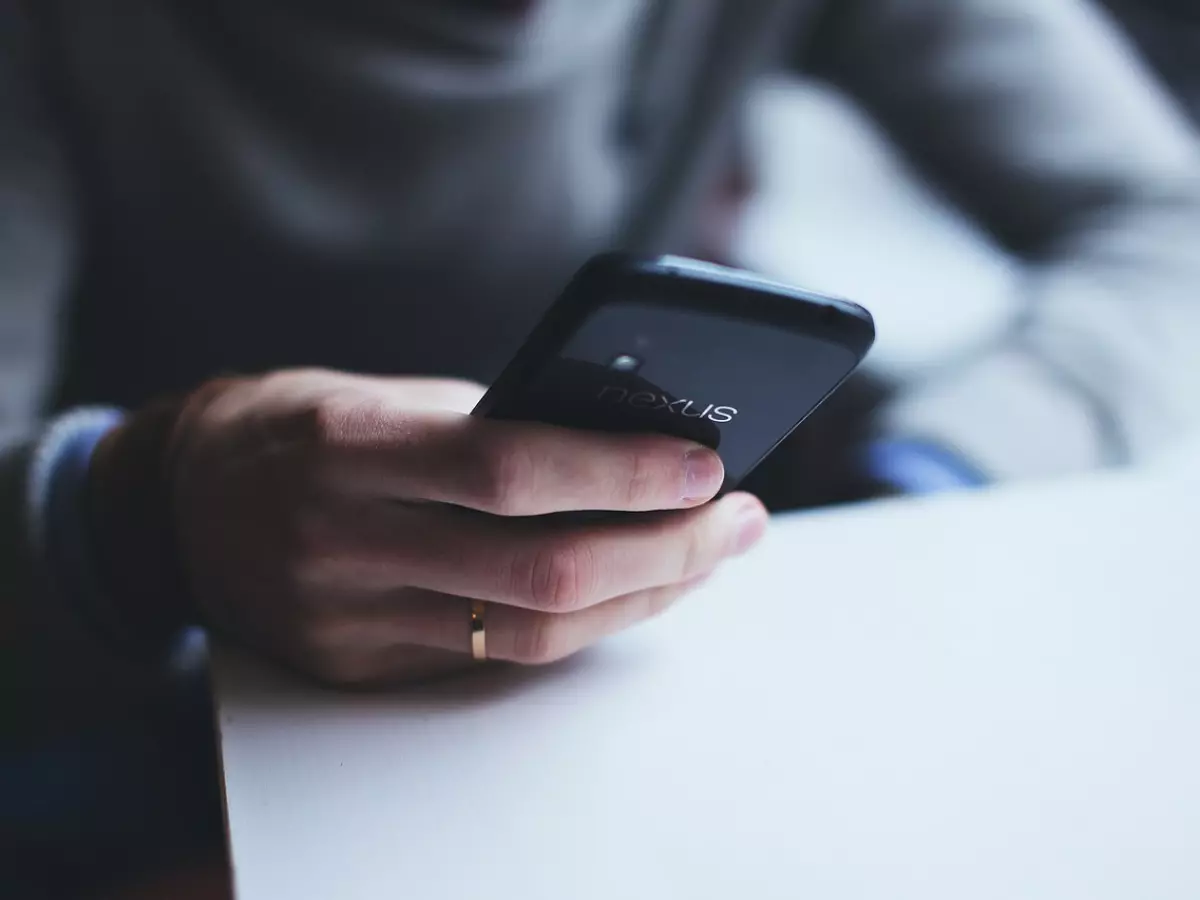 A person holding a black smartphone with the word 'nexus' on the back.