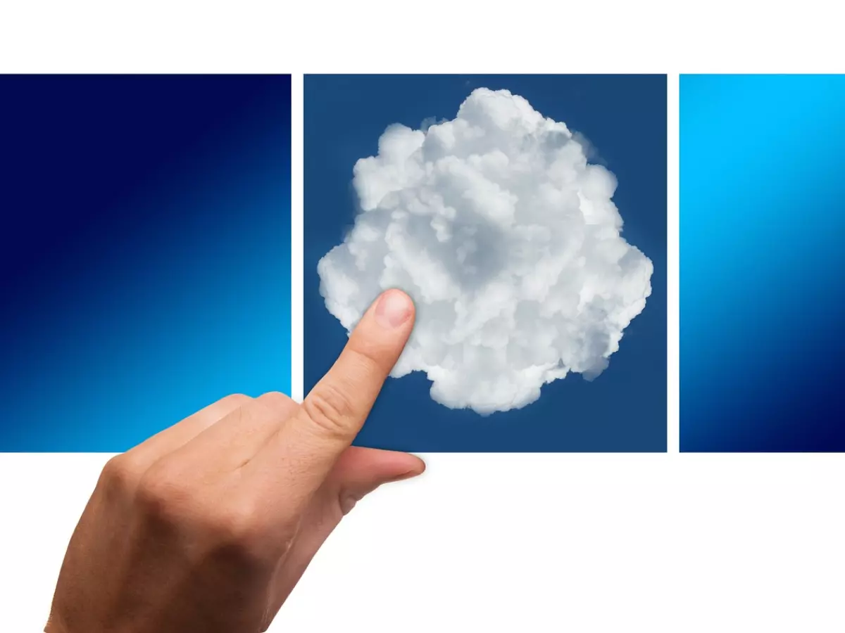 A hand pointing to a white cloud on a blue background. There are two other blue squares on either side of the cloud.