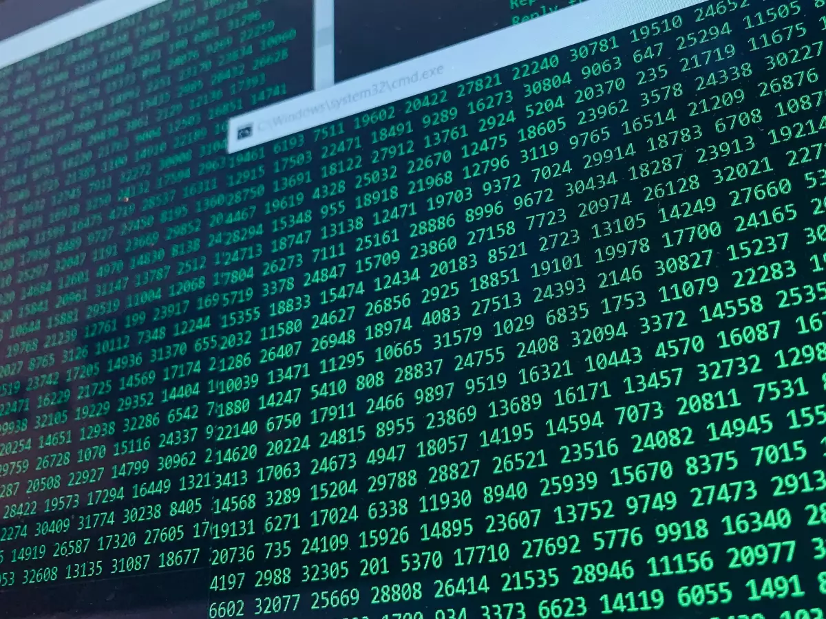 A close-up shot of a computer screen displaying a continuous stream of numerical data in shades of green on a dark background.