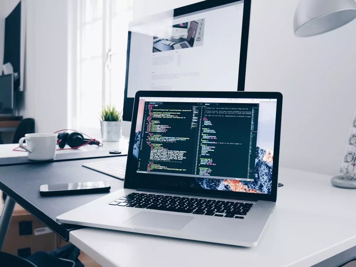 A laptop open on a desk with code on the screen.