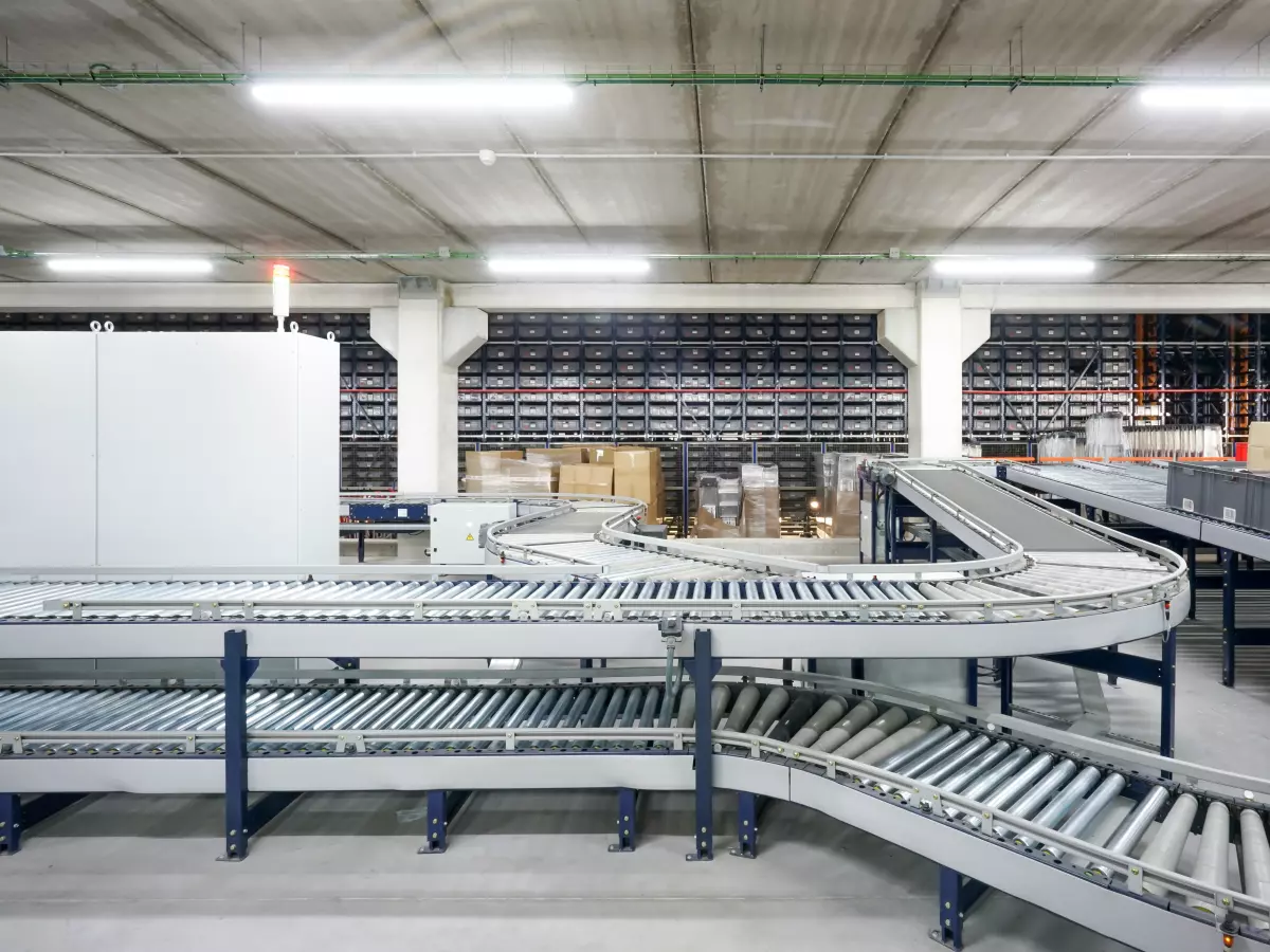 A complex network of conveyor belts winding through a warehouse, showing the interconnectedness of automated material handling. The image conveys efficiency and advanced technology.