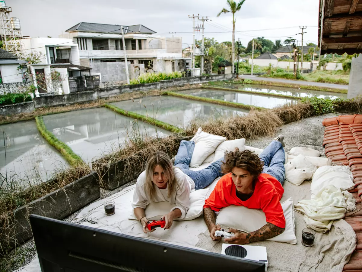 Two people are lying on a patio, looking at a TV, enjoying a game