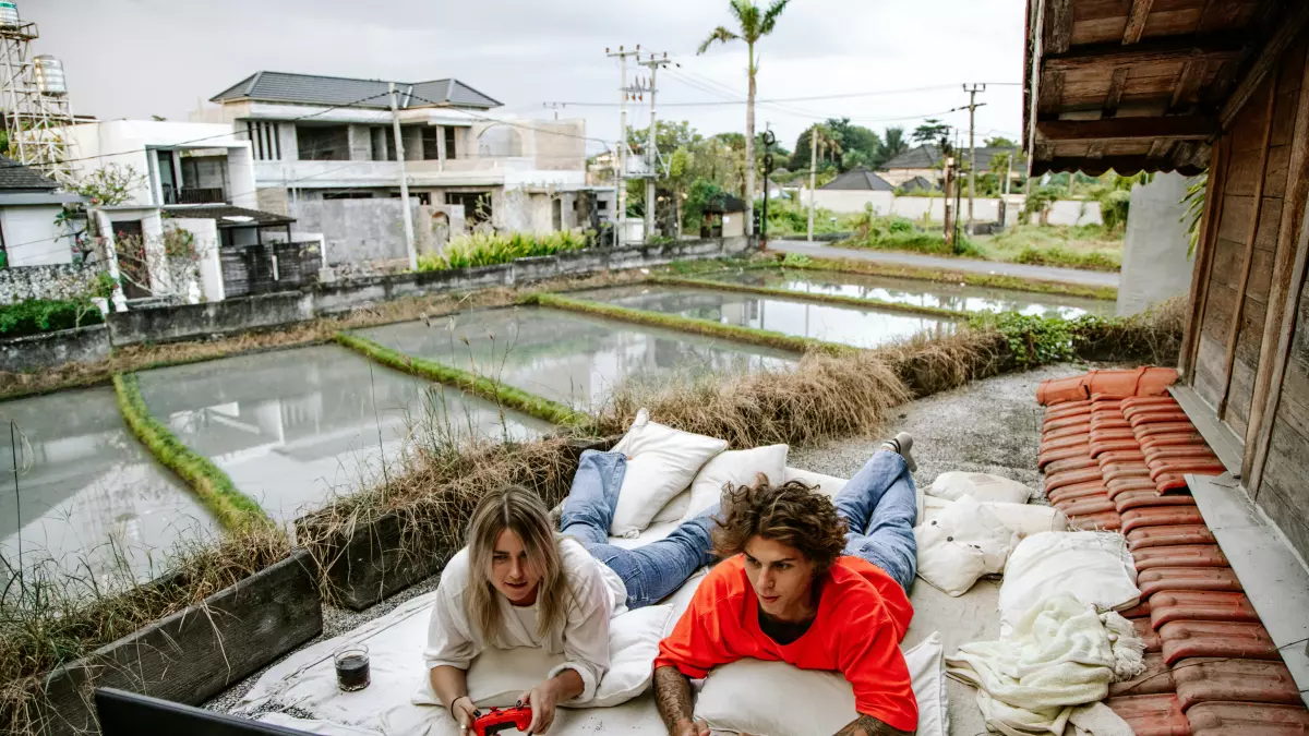 Two people are lying on a patio, looking at a TV, enjoying a game