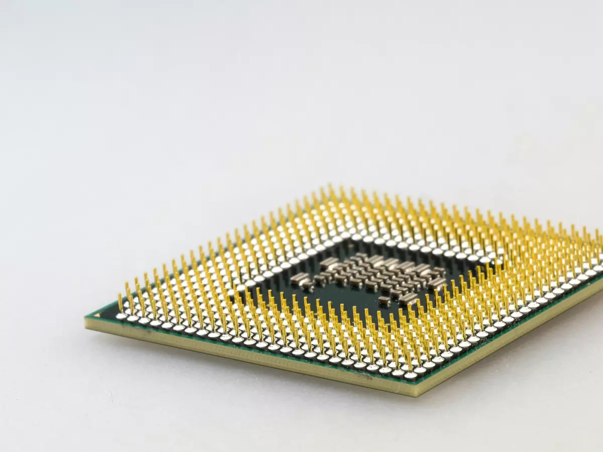 A close-up image of a computer processor chip, with gold pins and a square shape.