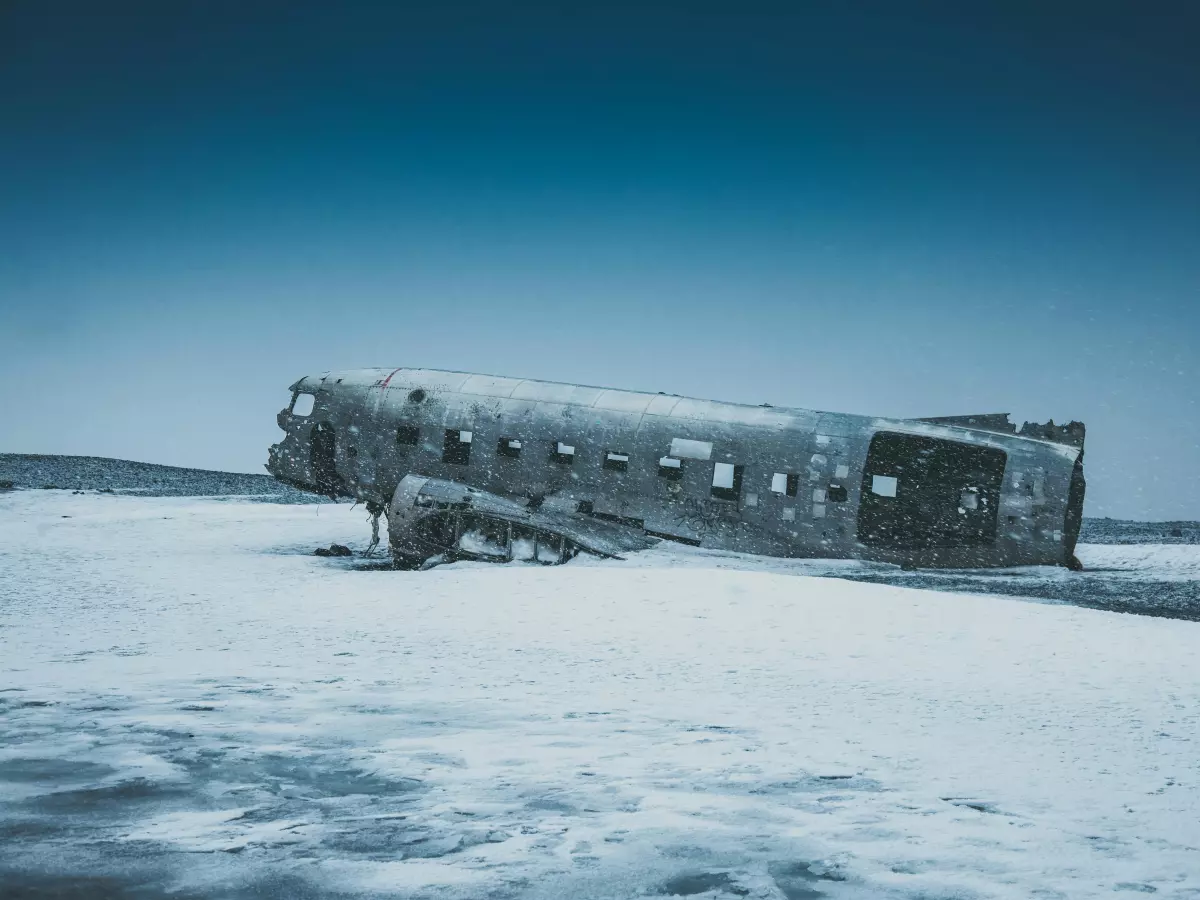 A wrecked airplane lying on a snowy beach.