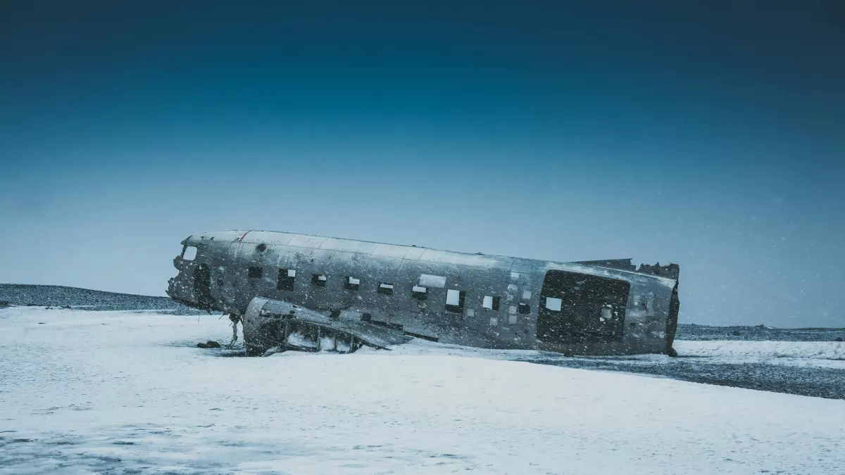 A wrecked airplane lying on a snowy beach.