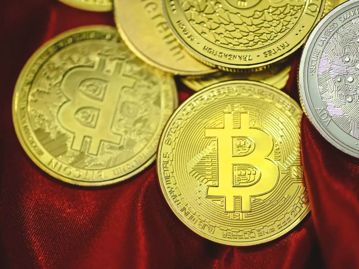 A close-up shot of several Bitcoin coins, one of them prominently displayed in the center, lying on a red fabric background.