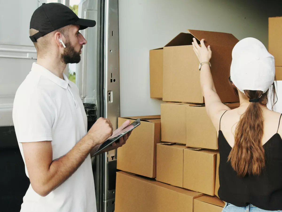 A man and a woman checking boxes inside a delivery truck.