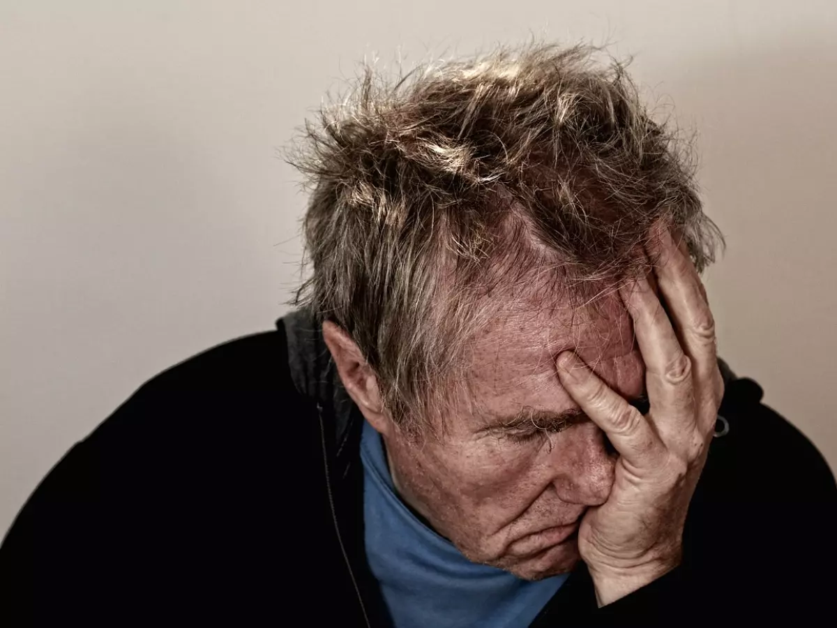 A man holding his head in his hands, looking defeated and frustrated, with his hair tousled.