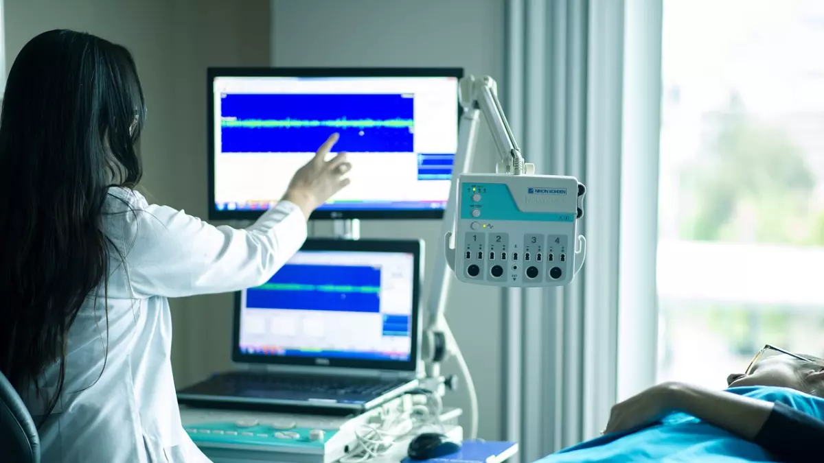 A doctor is looking at a monitor in a medical setting. 