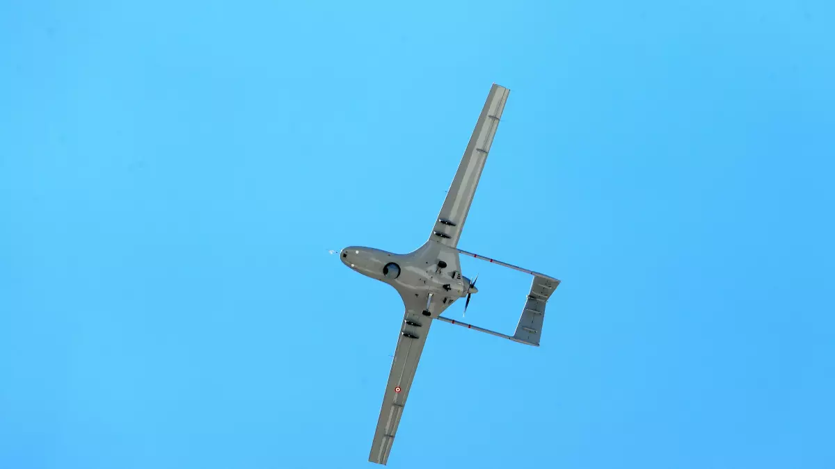 A drone flying in the sky against a clear blue background